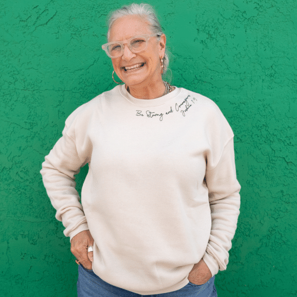 Cream pullover sweatshirt with black script writing on collar and shoulder with scripture "be strong and courageous Joshua 1:9:" for casual ladies fashion.