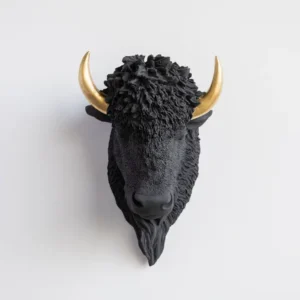 "Decorative black bison wall mount featuring a textured resin fur-like finish, sculpted facial details, and metallic gold horns, displayed against a light-colored wall."