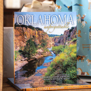 'Oklahoma Unforgettable' Coffe Table book cover showing an Oklahoma canyon landscape with a river flowing between red rock cliffs.